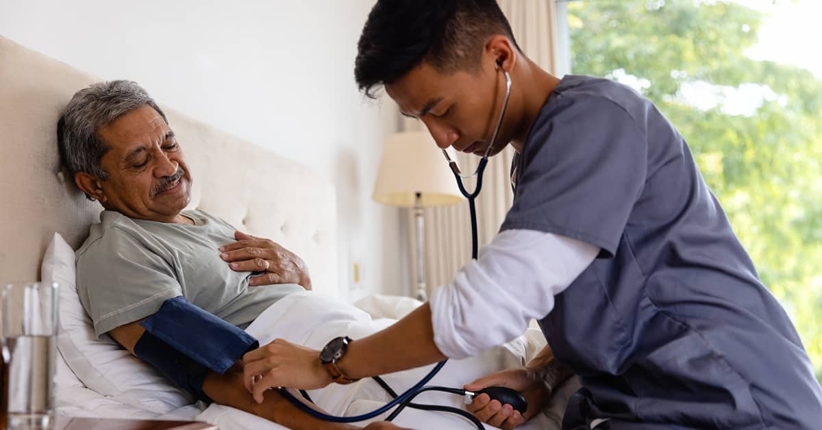 male mobile health nurse measuring blood pressure from a male patient at home